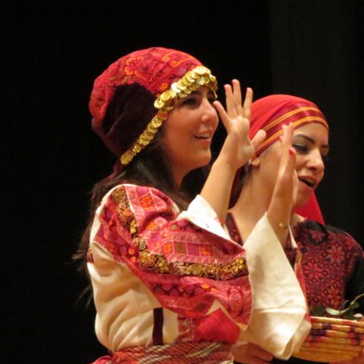 Dancers in embroidered traditional dress clapping on stage